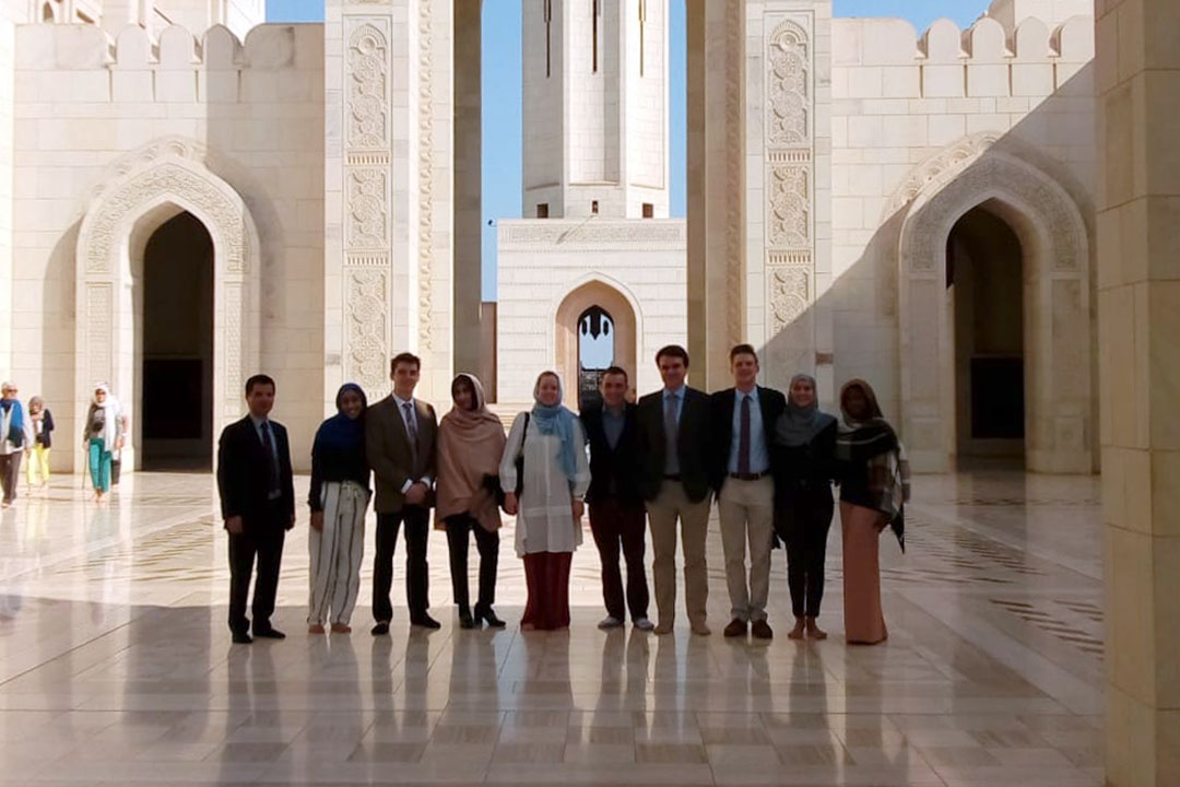 A group of students outside a huge white stone building with tiled floors
