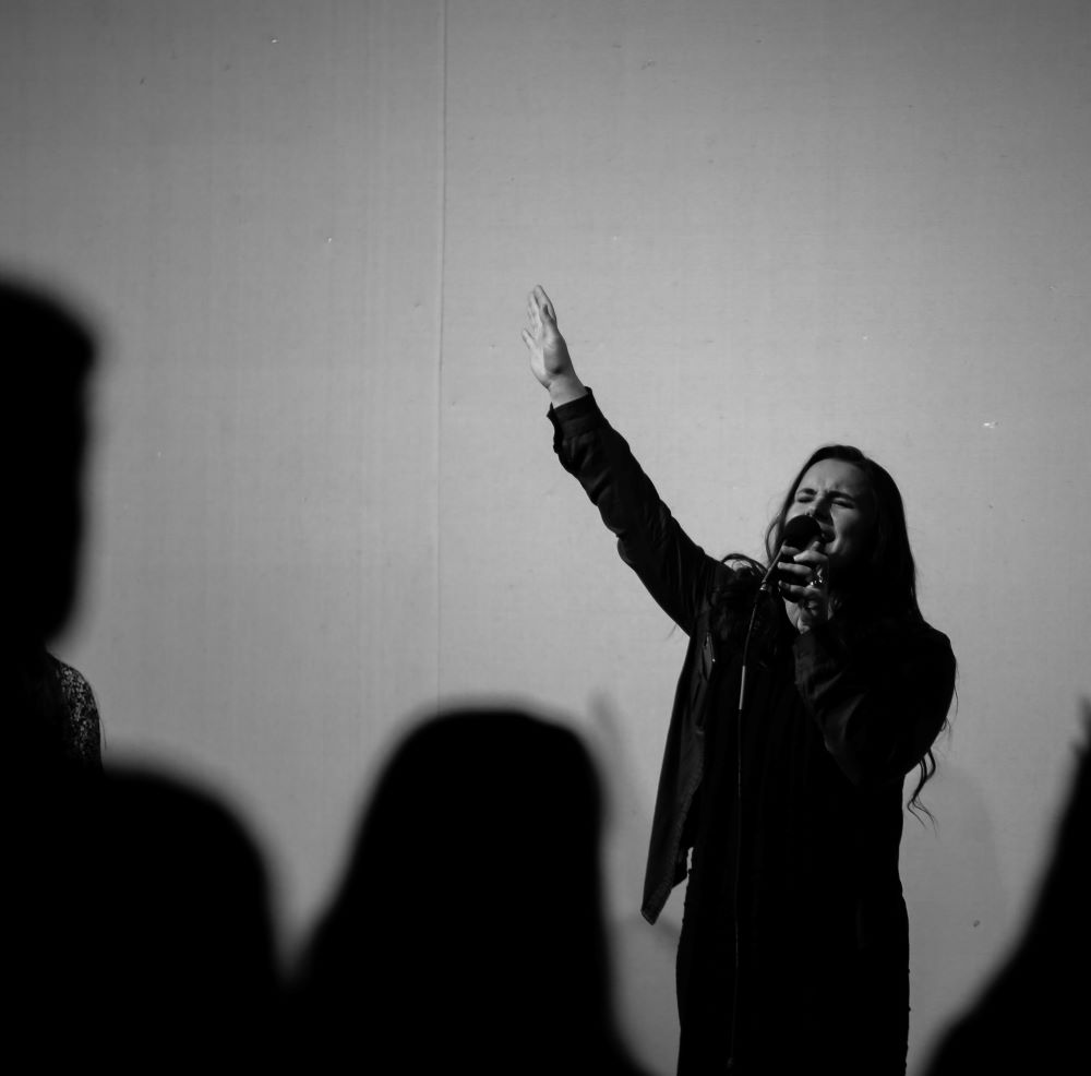 Woman raising her hand in worship while holding microphone