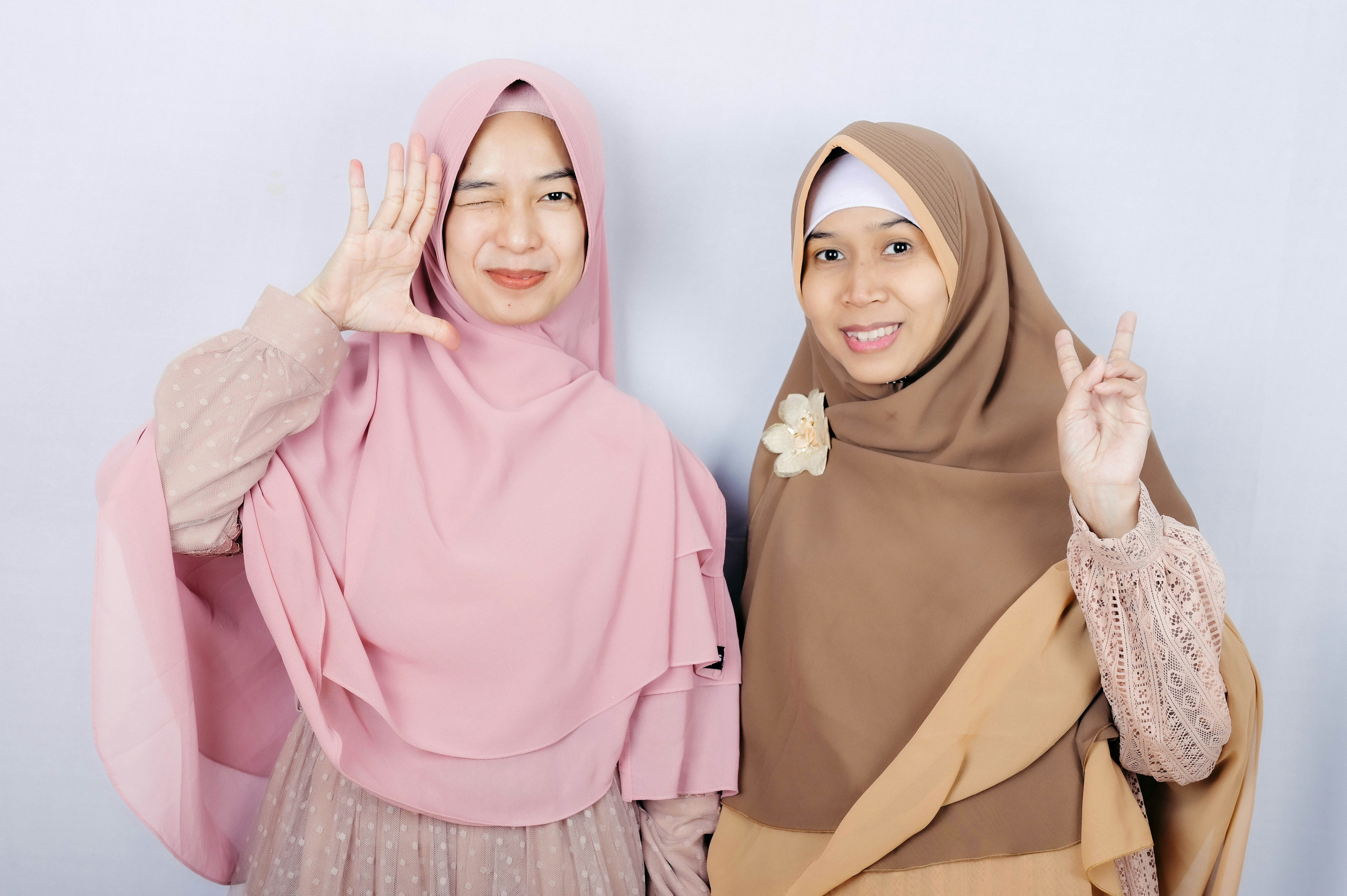 Two Muslim women giving peace signs