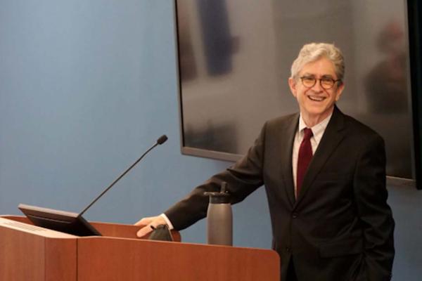 Paul Duff in a suit and tie smiling at a podium
