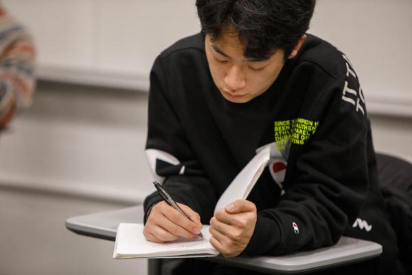 Undergraduate student in a Buddhist Philosophy class writing in a notebook