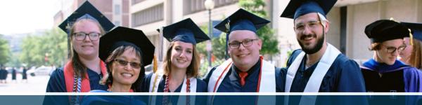 A group of Religion graduates and a faculty member stand outside in graduation caps and gowns